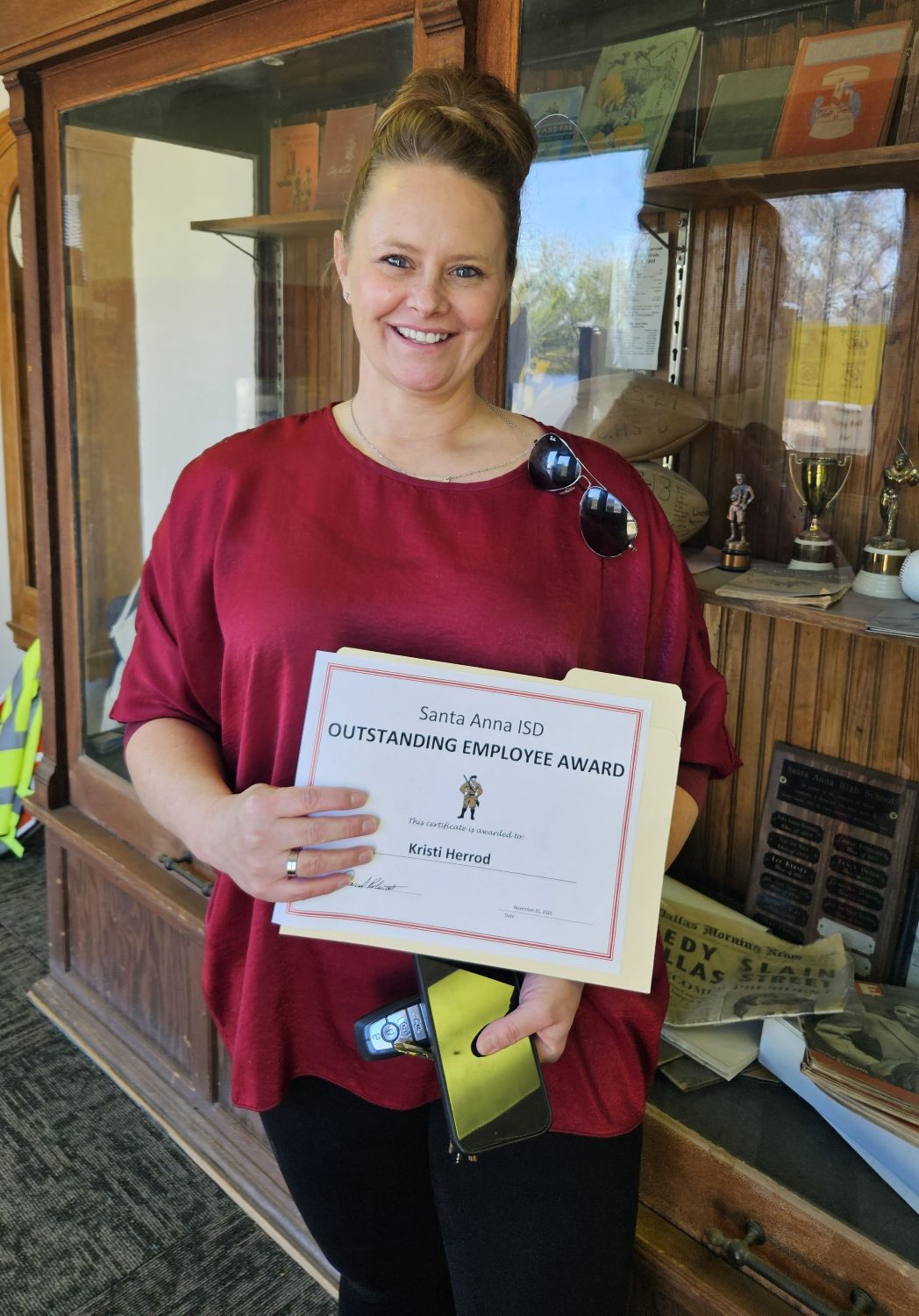 woman in red blouse smiling while holding a certificate